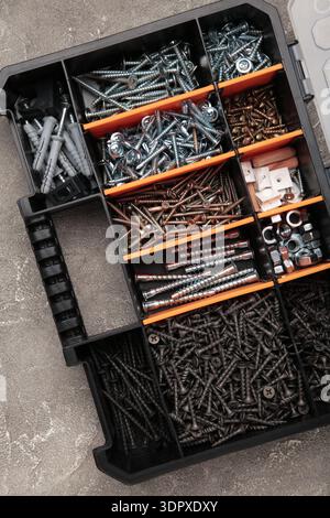 Yellow case with small construction objects on grey background. Vertical photo Stock Photo