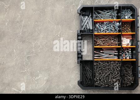 Yellow case with small construction objects on grey background. Space for text Stock Photo