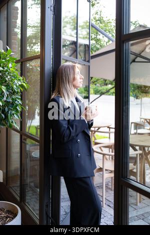 Relaxed pensive businesswoman small business owner drinking coffee and thinking about new goals. Stock Photo