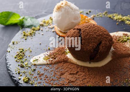Dessert With Chocolate Cake, Ice Cream, and Nuts Served on a Black Plate in a Restaurant Stock Photo