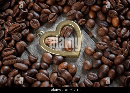 A heart-shaped keychain surrounded by roasted coffee beans. Close-up. The concept of love for coffee Stock Photo