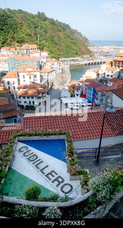 Aerial view of Cudillero, a picturesque coastal town in Asturias, Spain. The scene captures vibrant buildings with terracotta roofs and a lush green h Stock Photo