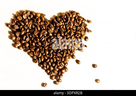 Roasted coffee beans arranged in heart shape on light background, love coffee concept with copy space, minimal romantic food composition Stock Photo