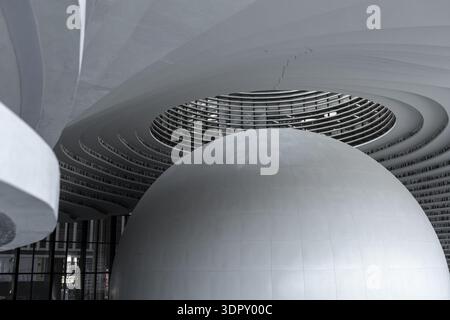 Binhai, China - 08 December 2025: View of the Binhai Library's luminous, spherical auditorium piercing through the multi-tiered, wave-like bookshelves Stock Photo