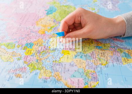 Hand Placing a Marker on a World Map Showing Various Countries and Regions Stock Photo
