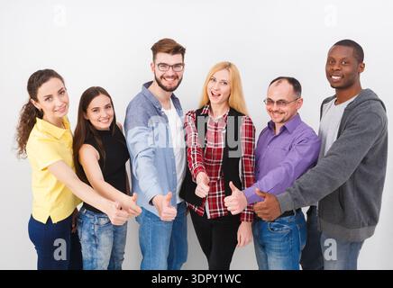 Group of Friends Giving Thumbs up While Standing in a Row Against a Plain Background Stock Photo