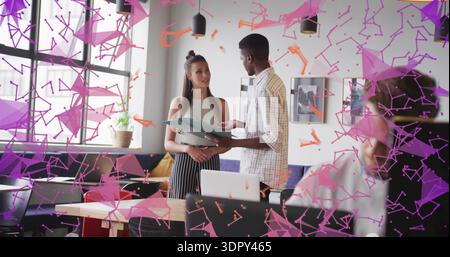 Talking man in checked shirt, intern in tank top at office table, holding green folder, laptop Stock Photo