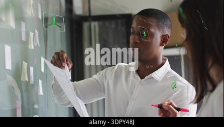 Holding paper man wearing white shirt placing it at glass planning board, with sticky notes Stock Photo