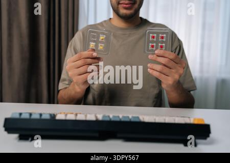 Cropped shot portrait of man holding mechanical keyboard switches, choosing between different types for custom keyboard building and maintenance Stock Photo