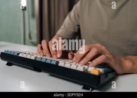 Cropped shot of person hands typing on stylish wireless mechanical keyboard with colored keycaps, demonstrating efficient digital work, productivity Stock Photo