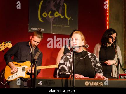 Babsea CD presentation Live music performance on small stage: female singer at keyboard with microphone, guitarist playing beside her Stock Photo