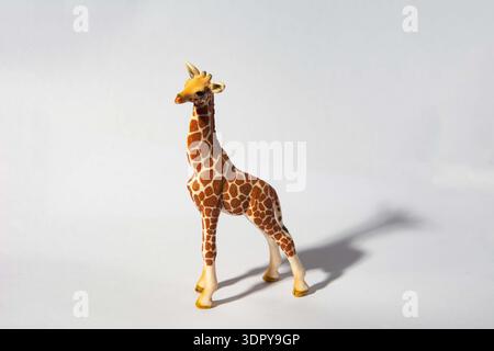 Schleich toy giraffe figurine.A toy giraffe figure with a detailed pattern, standing against a plain background. Stock Photo