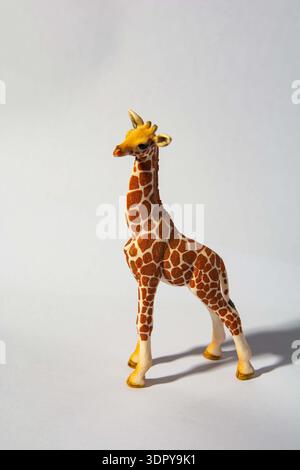 Schleich toy giraffe figurine.A toy giraffe figure with a detailed pattern, standing against a plain background. Stock Photo