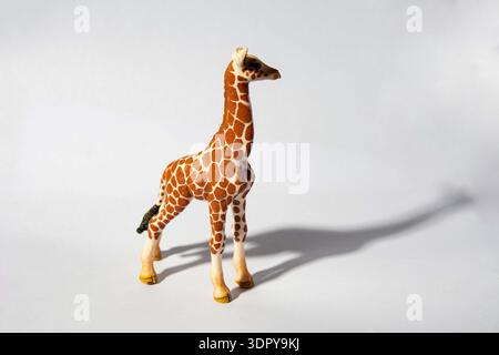 Schleich toy giraffe figurine.A toy giraffe figure with a detailed pattern, standing against a plain background. Stock Photo