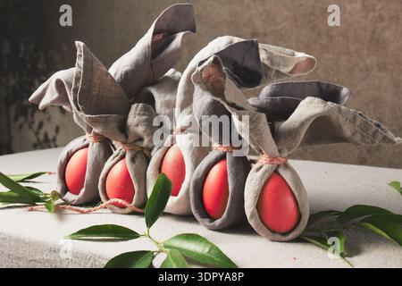 Easter table setting with decorated eggs wrapped as bunnies on a grey cloth background  Stock Photo