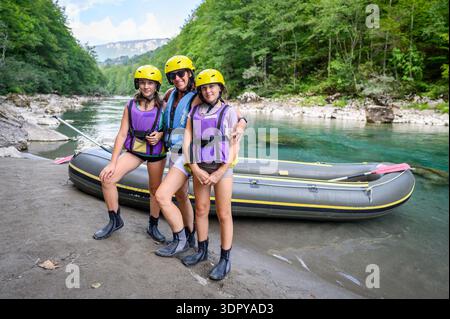 A family wearing yellow helmets and life vests sits inside a transport van, preparing for a white-water rafting adventure on the Tara River in Stock Photo