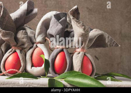 Easter table setting with decorated eggs wrapped as bunnies on a grey cloth background  Stock Photo