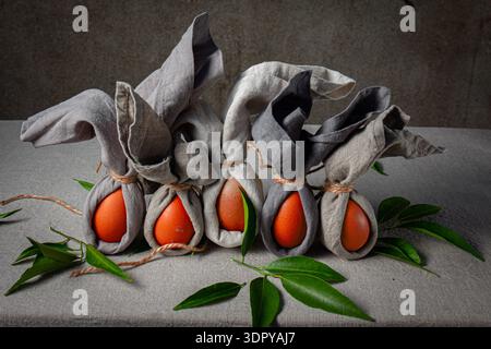 Easter table setting with decorated eggs wrapped as bunnies on a grey cloth background  Stock Photo