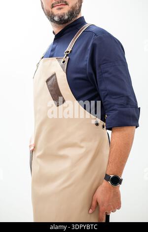 Beige chef apron with leather chest pocket and suspenders on navy jacket. Stock Photo
