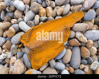 A small fragment of rusting metal on a pebble beach Stock Photo