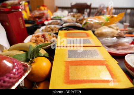 Chinese New Year festive table with red envelopes, fruits, roasted chicken, and traditional dishes in home setting Stock Photo