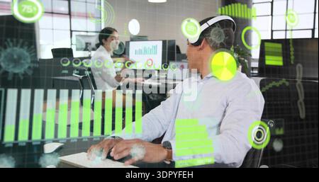 Interacting man wearing light shirt AR headset using green charts in open office, with monitors Stock Photo
