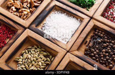 Different Spices and Nuts in Small Wooden Containers Arranged in a Grid on a Table Stock Photo