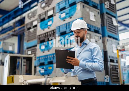 A portrait of project manager or engineer with clipboard in a factory, working. A portrait of a project manager or engineer with clipboard in a factor Stock Photo