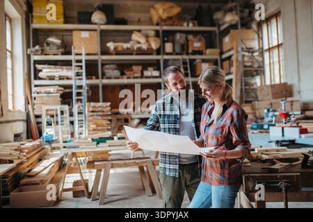 Two carpenters man and woman talking about design of products. Small business concept. Two carpenters a man and a woman talking about design of produc Stock Photo