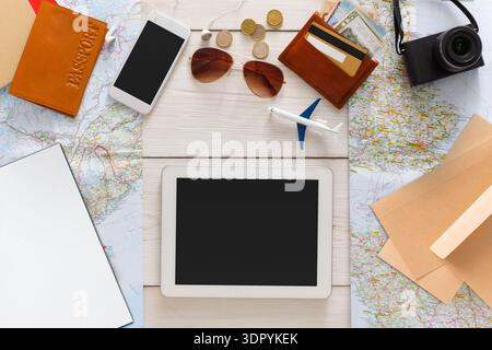 Travel Items on a Table With Maps, Devices, and Money During Vacation Planning Stock Photo