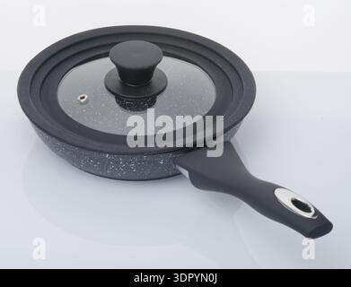 A modern multi stove frying pan. One which works on gas, electric, halogen & induction hobs. Cooking pan with granite coating. Cooking pan with lid. Stock Photo