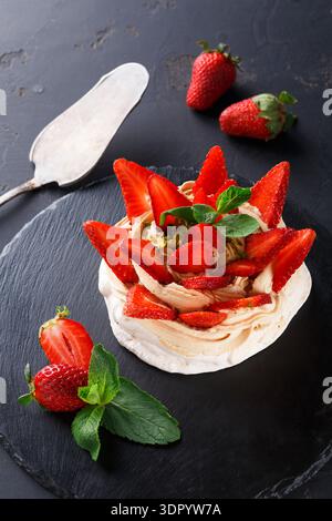 Fresh Strawberries on Meringue Dessert With Mint Leaves on a Black Stone Plate Stock Photo