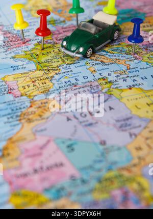 Small Green Car on a Map With Colorful Push Pins Marking Different Locations in Europe and Africa Stock Photo