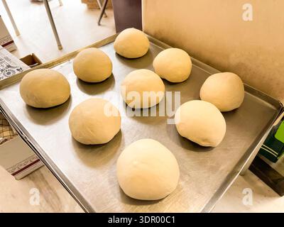Homemade bread dough balls on a baking tray and dough kneading process in a mixer. Stock Photo