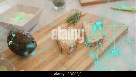 Displaying wooden board with rustic bread, avocado, rosemary, crumbs on stone counter, teal overlay Stock Photo