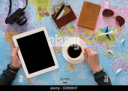 Planning a Trip With a Map, Tablet, Coffee, and Travel Essentials on a Table Stock Photo