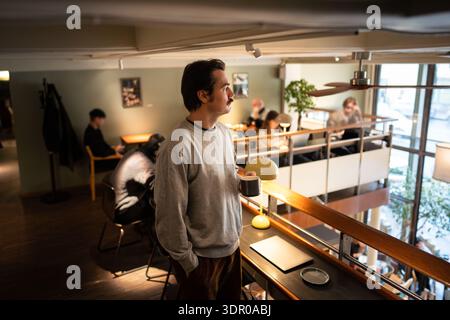 Thoughtful relaxed businessman drinking coffee at co-working, spending free time in lively city cafe Stock Photo