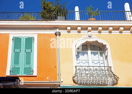 Colourful townhouse façade in Nice, South of France, with green shutters, ornate wrought iron balcony and decorative window details Stock Photo