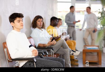 Young male visitor sitting on the bench in waiting room of clinic Stock Photo