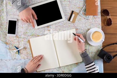 Planning a Trip With Maps, Devices, and Notes on a Wooden Table in a Bright Setting Stock Photo