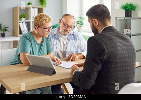 Senior couple signing a contract with advisor during meeting and paperwork review Stock Photo