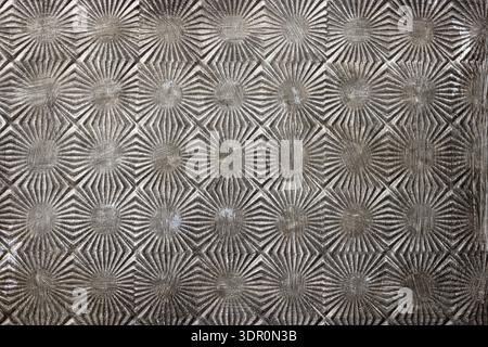 Close-up of vintage metal surface with repeating geometric embossed pattern. Worn and aged texture suitable for background, wallpaper, industrial desi Stock Photo