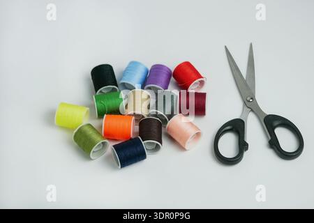 Colorful sewing thread spools with scissors on white background. Tailoring, DIY craft and handmade concept. Studio shot with copy space, high resoluti Stock Photo