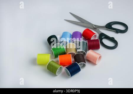 Colorful sewing thread spools with scissors on white background. Tailoring, DIY craft and handmade concept. Studio shot with copy space, high resoluti Stock Photo