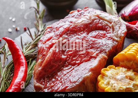 Fresh Beef Steak With Vegetables and Spices on a Black Cutting Board in a Kitchen Setting Stock Photo