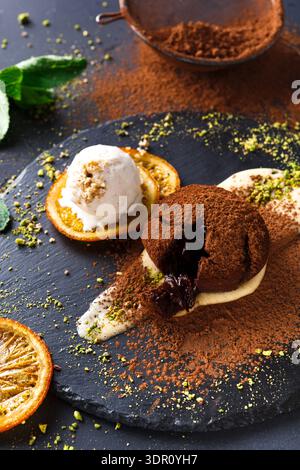 Dessert With Chocolate Cake, Ice Cream, and Orange Slices on a Black Plate Stock Photo
