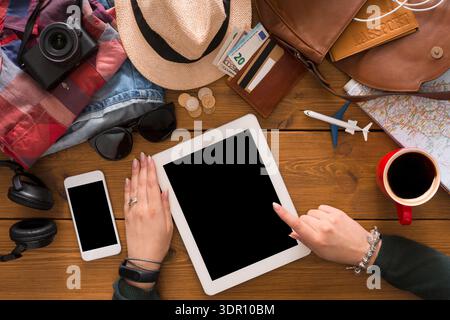 Planning a Trip With Digital Devices and Travel Items on a Wooden Table Stock Photo