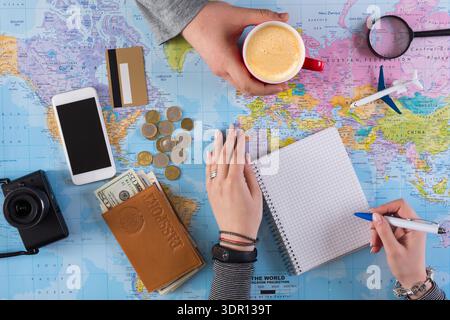 Planning a Trip With Maps, Notes, and Coffee in a Busy Workspace Stock Photo