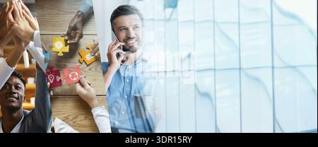 Businessman Works Online and Shares Laughter With Colleagues in Modern Office Setting Stock Photo