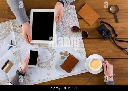 Planning a Trip With Maps, Devices, and Travel Items on a Wooden Table Stock Photo